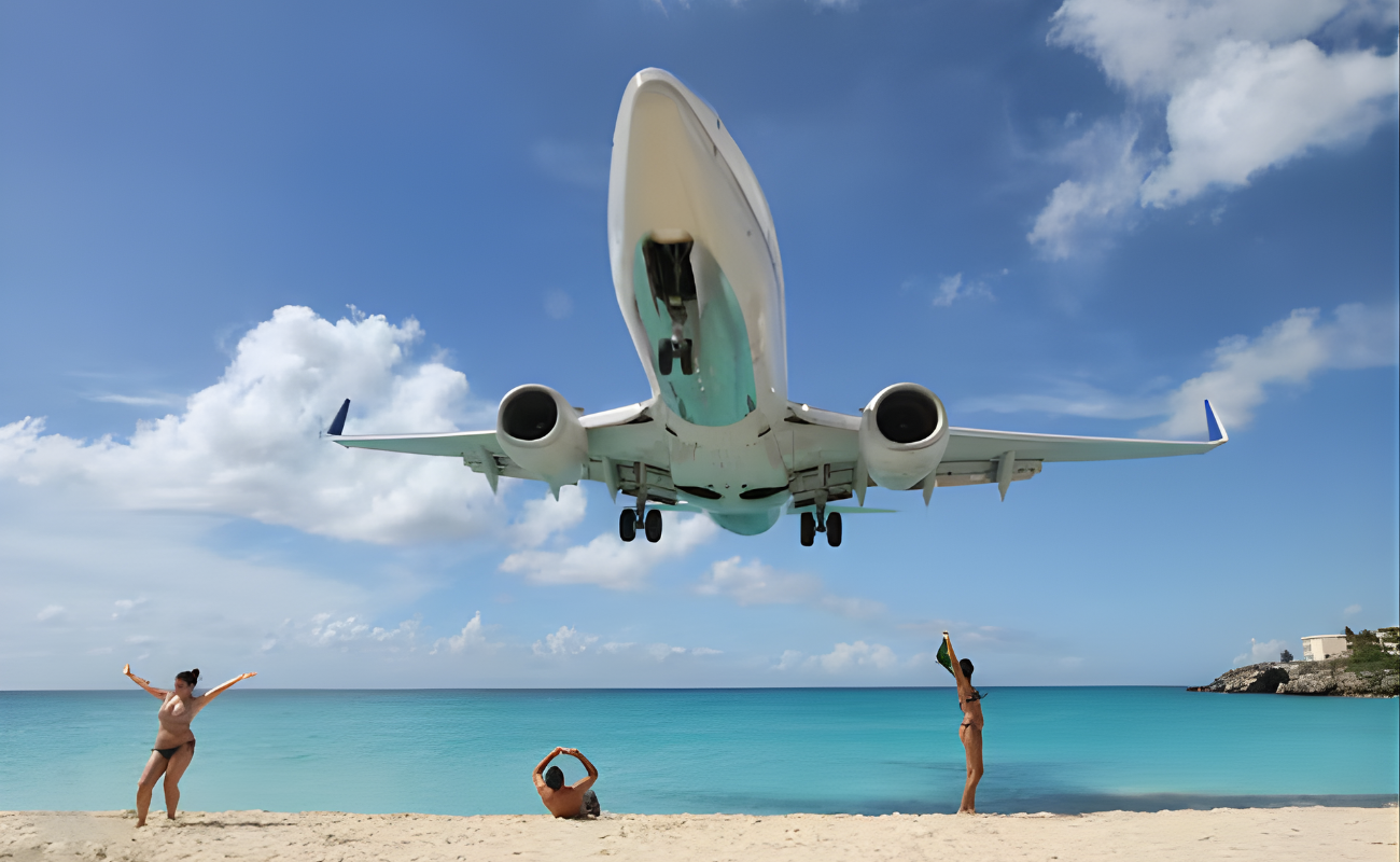 Low-flying airplane over a beach with travelers below, illustrating cheap flights to beach destinations and popular routes near coastal airports.