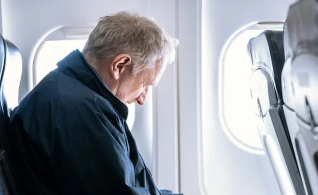 Older traveler seated by an airplane window, illustrating why travel insurance is important for senior and long-haul air travel.