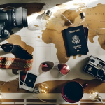 Flat-lay travel essentials on a world map passport, cameras, and string lights representing travel insurance planning for international trips.
