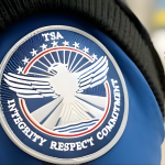 Close-up of TSA uniform badge emphasizing integrity and commitment, with "TSA ConfirmID" overlay related to new identity verification fee.
