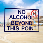 Airport security sign stating no alcohol allowed beyond this point near terminal gates.