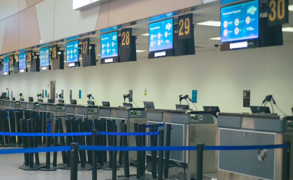 Empty airport check-in TSA counters with digital screens and queue barriers