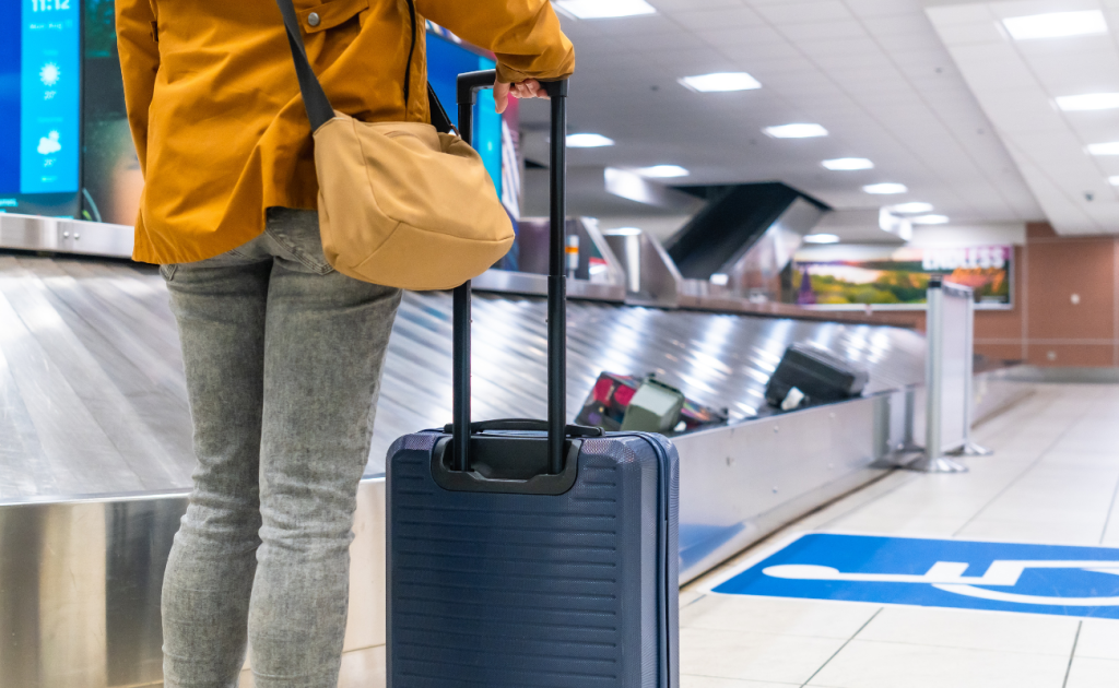 Passenger without an ID standing at baggage claim holding a suitcase handle