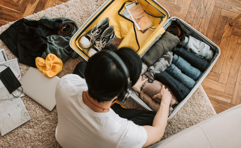 Solo traveler packing clothes neatly into a suitcase at home before a Europe trip