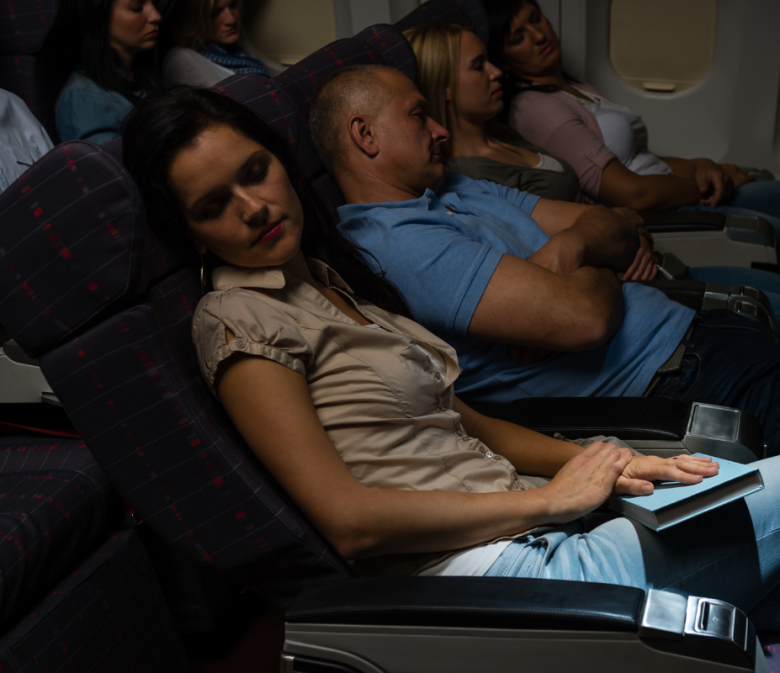 Multiple passengers sleeping in economy seats during red-eye flights sleep on overnight flights.