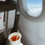 Two takeout drinks on an airport table overlooking a snowy tarmac and parked airplane reminder to finish before security when bringing food through TSA.
