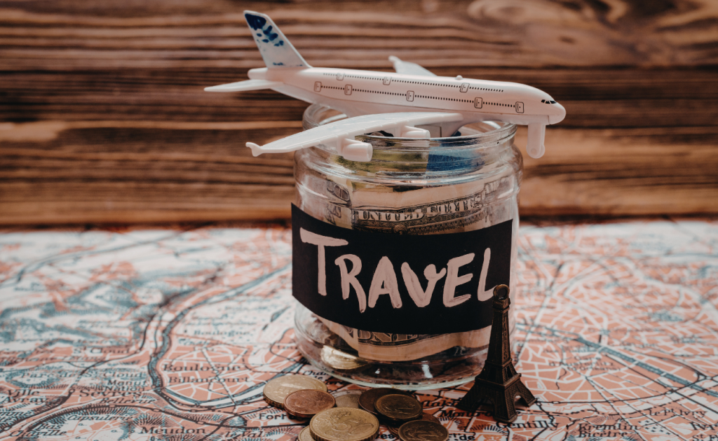 Model airplane placed on a jar of savings money for budget travel planning