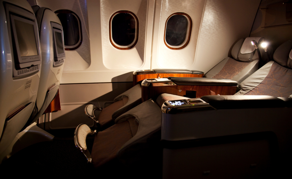 Lie-flat business class seats with personal screens and privacy dividers inside an aircraft cabin
