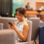 Passenger checking phone at airport while following 2026 airline check-in rules and deadlines.