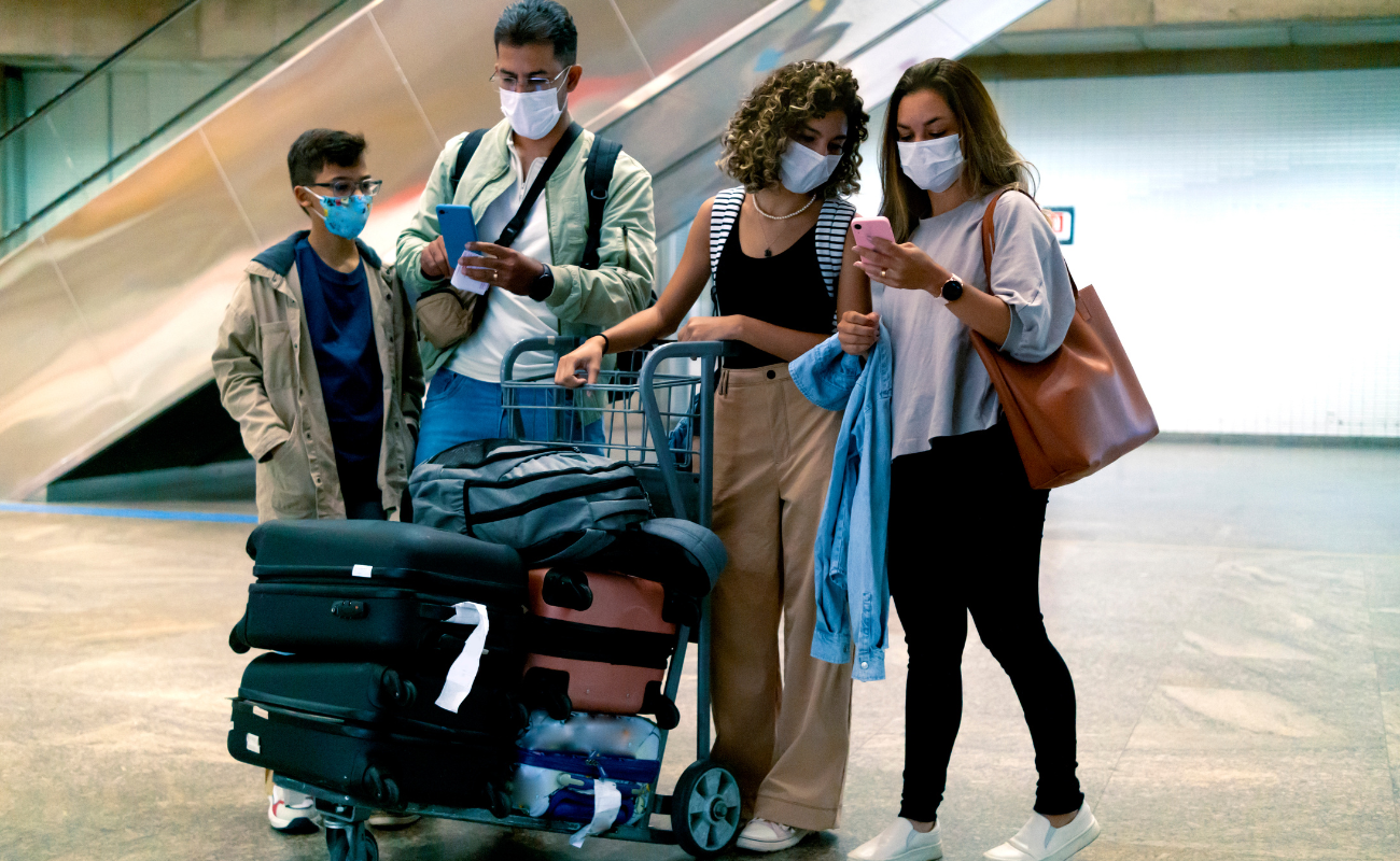 Travelers arriving early at the airport checking flight details before security screening.