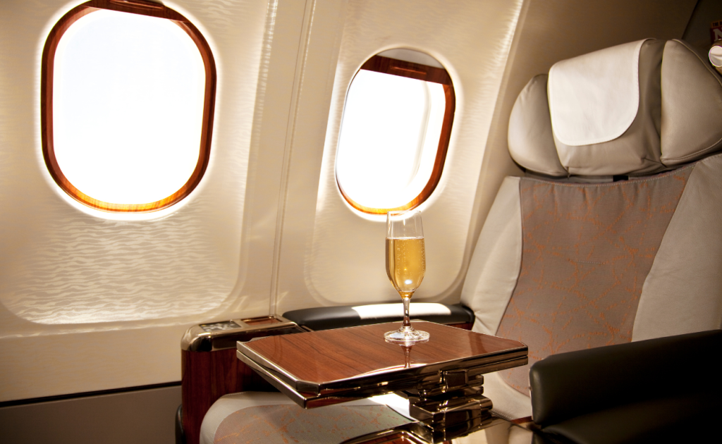 Business class airline seat with a glass of champagne on a fold-out table by the window