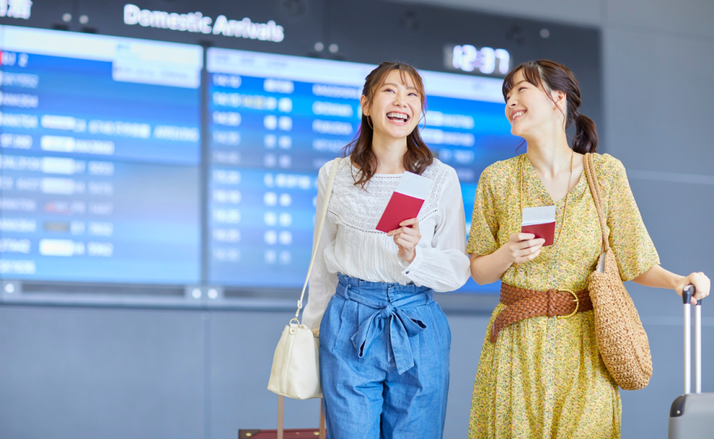 Passengers arriving early at the airport holding passports near the flight information board.