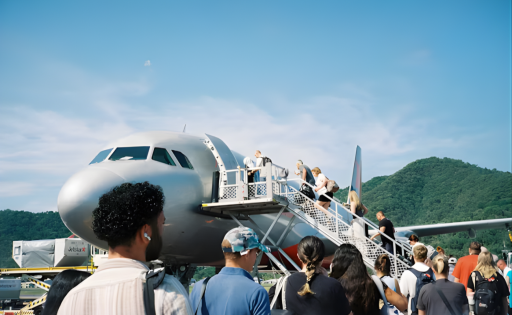 Passengers boarding airplane via outdoor stairs, carrying bags highlighting potential hidden airline fees for carry-ons.