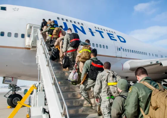 Military personnel boarding a United Airlines aircraft using mobile stairs.
