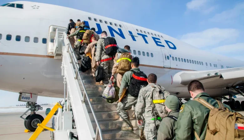 Military personnel boarding a United Airlines aircraft using mobile stairs.