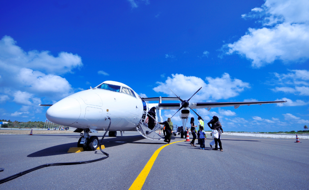 Passengers boarding a small turboprop airplane on the airport tarmac under a clear blue sky after flight tarmac delays
