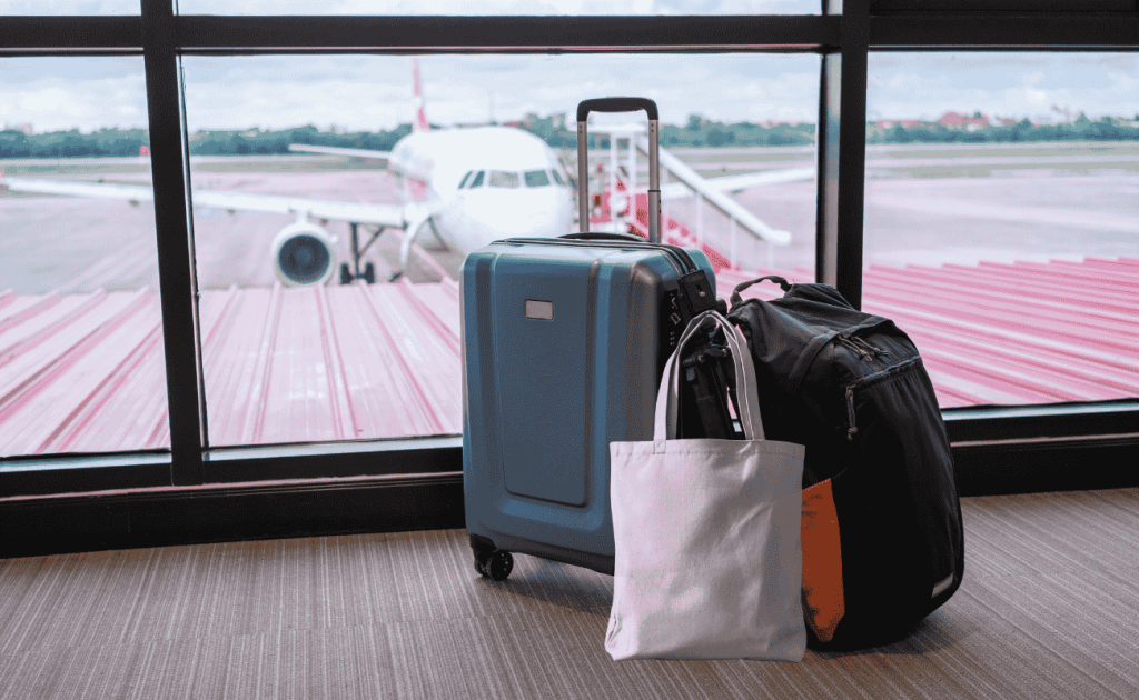 Tote bag placed with carry-on luggage at airport gate under airline personal item rules.