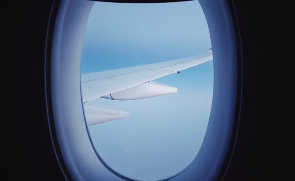 Airplane window seat with clear sky view