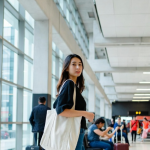 Traveler carrying a tote bag in an airport terminal under 2026 airline personal item rules.