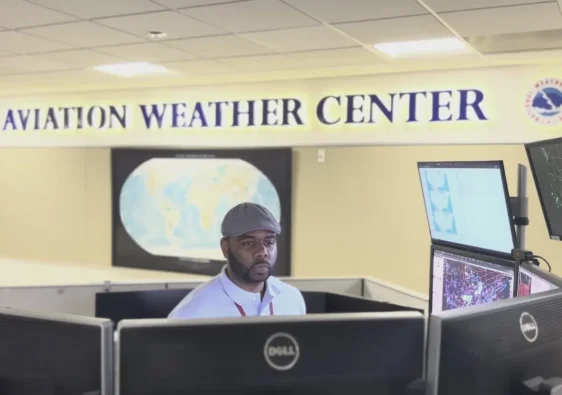 Meteorologist working inside an aviation weather center monitoring pilots flight safety data