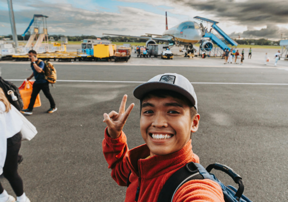 Traveler on airport runway near boarding stairs and aircraft, illustrating smart airport travel tips