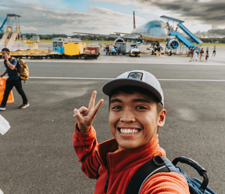 Traveler on airport runway near boarding stairs and aircraft, illustrating smart airport travel tips