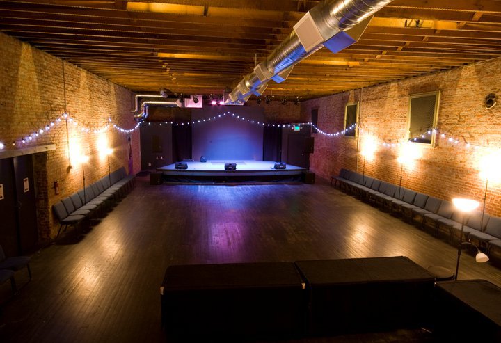 he stage at Raw Space in Ellensburg with exposed brick walls and string lights — a community venue hosting music, comedy, and civic events