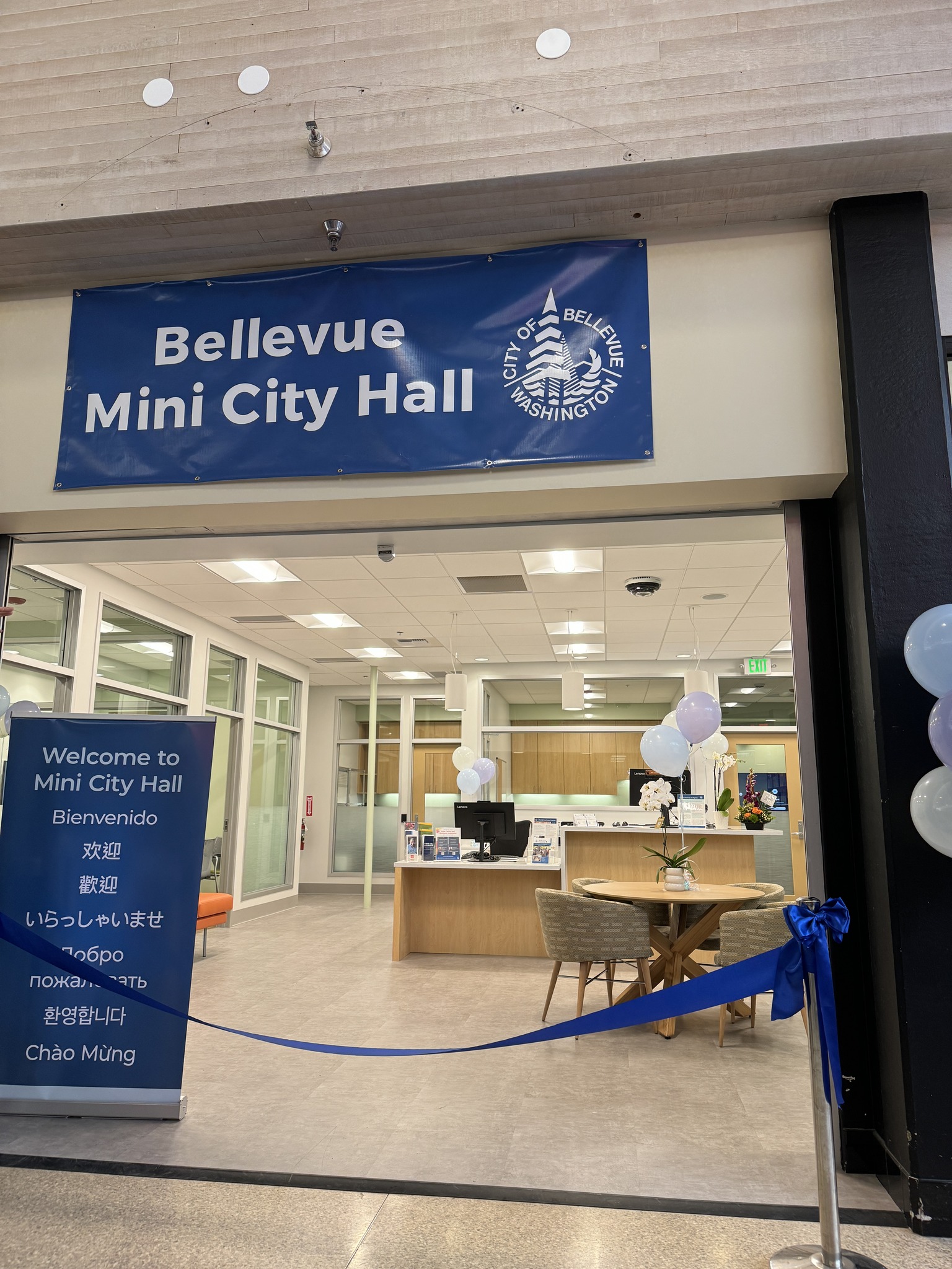 Bellevue's Mini City Hall inside Crossroads Mall, with welcome signs in eight languages — civic infrastructure meeting people where they already gather.