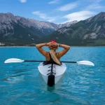 solo alone woman travelling kayak in the middle of the lake